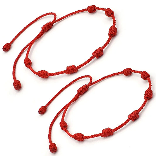 Dos pulseras de 7 nudos en hilo rojo entrelazadas, simbolizando un profundo vínculo de amor y protección para la pareja