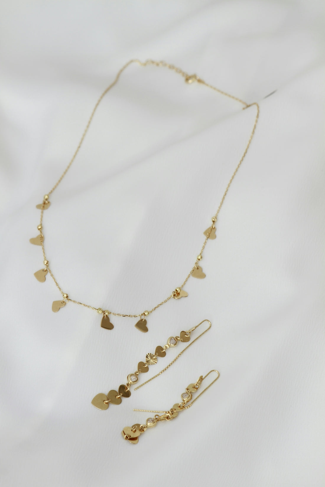 A necklace and earring set on a white sheet