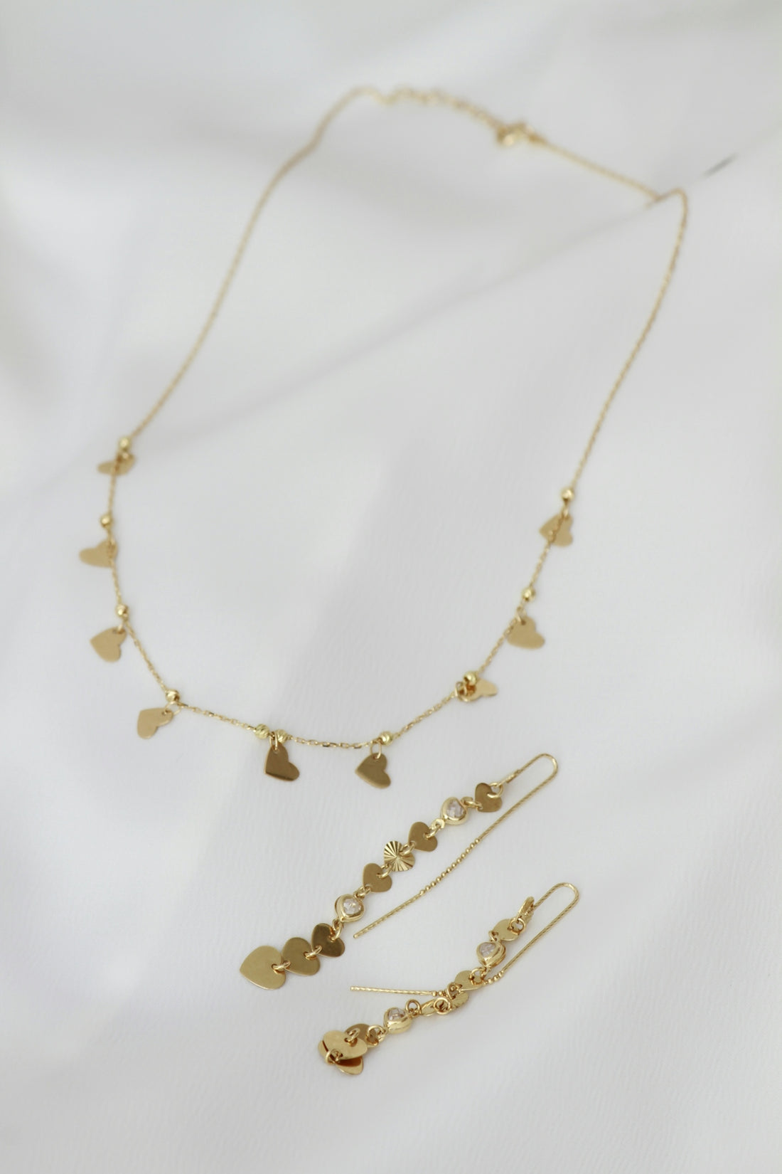 A necklace and earring set on a white sheet