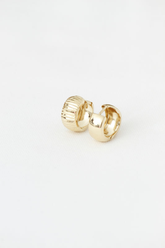 Two textured and smooth gold hoop earrings on white.